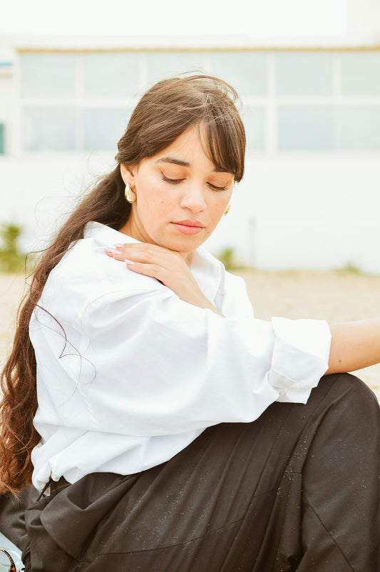 A woman sitting on the ground with her hand on her shoulder